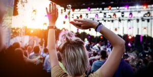 People with raised hands at summer music festival.