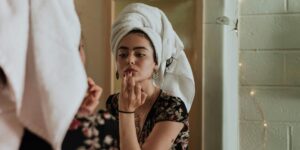 woman putting on makeup in the mirror